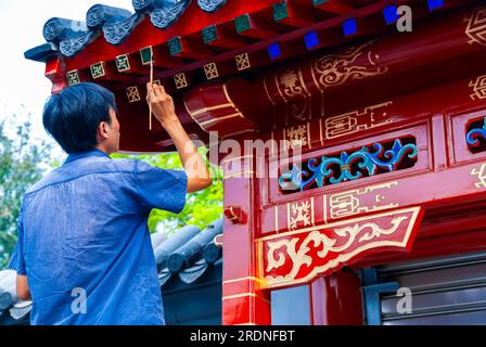 Peking, CHINA - Außenansicht, chinesischer Mann von hinten, arbeitet, malte Fassade des Souvenirshops in der Nähe des Yonghegong Lama-Tempels, traditionelle chinesische Malerei Stockfoto
