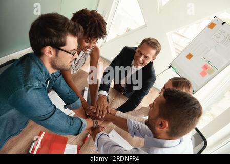Draufsicht von Geschäftsleuten, die sich im modernen Büro an den Händen halten Stockfoto