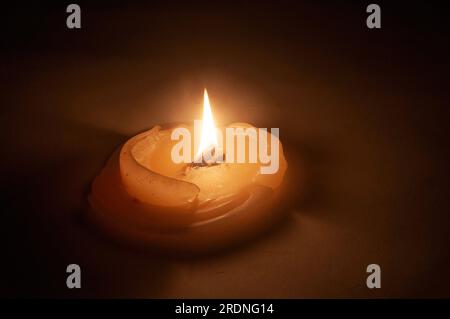 Große, abgebrannte Kerze mit einem dicken Docht. Wachs in einem breiten Ring. Studioaufnahmen auf dunklem Hintergrund. Wache-Kerze. Stockfoto