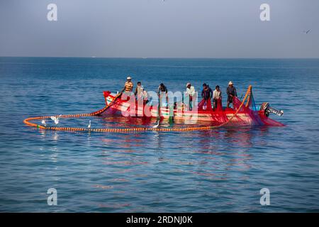 Indien, Kerala - 27. Dezember 2015: Indische Fischer ziehen die bemalte seine grafisch direkt in Boot 2. Netz lackiert in leuchtenden Farben, fliegende Seeschwalben, Holz Stockfoto