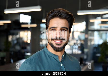 Lächelnder junger Geschäftsmann, der im Büro wegsieht, Porträt aus nächster Nähe. Stockfoto