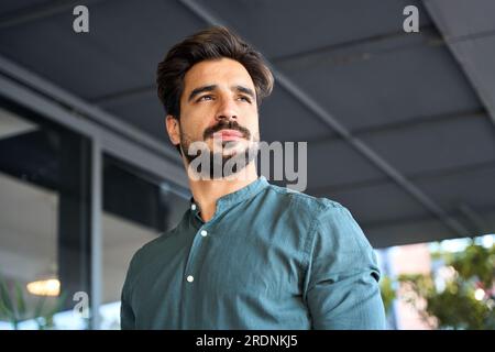 Ein zuversichtlicher lateinischer Geschäftsmann, der draußen steht und wegschaut, ein Porträt. Stockfoto