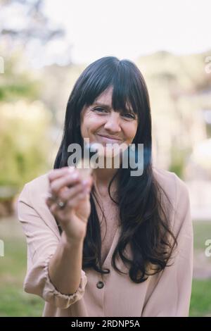 Eine Frau mit langen Haaren, die einen brennenden palo santo oder einen heiligen Baum hält. Stockfoto