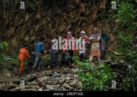 Srinagar, Kaschmir. 22. Juli 2023 22. Juli 2023, Srinagar Kaschmir, Indien : Menschen gehen auf einer beschädigten Straße nach Überschwemmungen in der Gegend von Faqir Gujri, am Stadtrand von Srinagar. Die Einheimischen behaupteten, dass mehrere Häuser Risse entwickelten und Maisfelder beschädigt wurden, es wurden jedoch keine Todesfälle gemeldet. Mehrere Regionen von Jammu und Kaschmir sind von anhaltenden starken Regenfällen heimgesucht worden, die zu mehreren Erdrutschen in den hügeligen Gebieten geführt haben und zur Schließung des Nationalautobahn Jammu-Srinagar geführt haben. Kredit: Eyepix Group/Alamy Live News Stockfoto