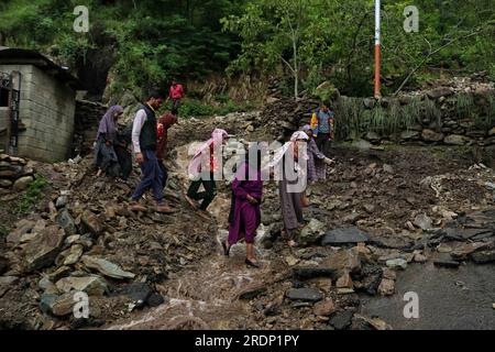 Srinagar, Kaschmir. 22. Juli 2023 22. Juli 2023, Srinagar Kaschmir, Indien : die Menschen gehen nach Überschwemmungen in Faqir Gujri am Stadtrand von Srinagar über eine beschädigte Straße. Die Einheimischen behaupteten, dass mehrere Häuser Risse entwickelten und Maisfelder beschädigt wurden, es wurden jedoch keine Todesfälle gemeldet. Mehrere Regionen von Jammu und Kaschmir sind von anhaltenden starken Regenfällen heimgesucht worden, die zu mehreren Erdrutschen in den hügeligen Gebieten geführt haben und zur Schließung des Nationalautobahn Jammu-Srinagar geführt haben. Kredit: Eyepix Group/Alamy Live News Stockfoto