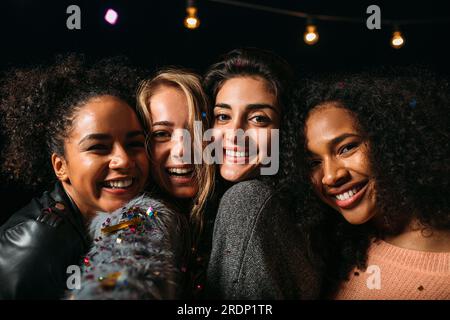 Porträt einer Gruppe verschiedener Frauen, die lächeln und nachts in die Kamera schauen Stockfoto