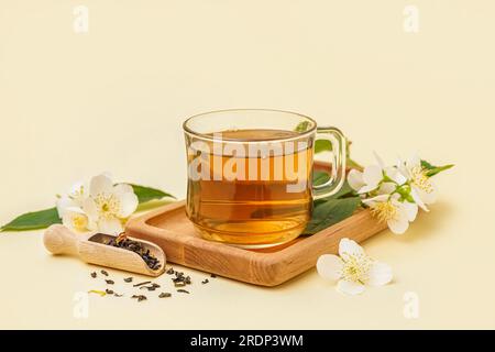 Tasse aromatischer Tee, getrocknete Blätter und wunderschöne Jasminblumen auf farbigem Hintergrund Stockfoto