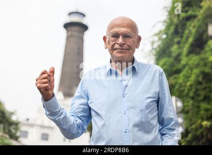 Köln, Deutschland. 21. Juli 2023. Günter Wallraff, Schriftsteller und Bürger von Ehrenfeld, steht vor dem Leuchtturm. Der einzige Leuchtturm Nordrhein-Westfalen steht im Kölner Ehrenfeld. Es hat keinen Zweck. Es ist einfach da - und vielleicht ist es deshalb so beliebt. Der bekannteste Ehrenfelder kämpft jetzt für eine Wiederbelebung. (Zu dpa/lnw: 'Der Leuchtturm von Köln-Ehrenfeld - ohne Bedeutung und doch geliebt') Kredit: Oliver Berg/dpa/Alamy Live News Stockfoto