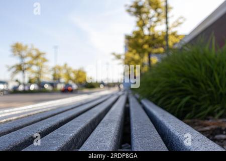 Graue Metallleiste - niedriger Winkel - unscharfer Hintergrund des Parkplatzes Stockfoto