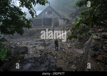 Menschen stehen in der Nähe einer beschädigten Straße nach Überschwemmungen im Gebiet von Faqir Gujri am Stadtrand von Srinagar, der Sommerhauptstadt von Indischer Kaschmir, am 22. Juli 2023. Die Einheimischen behaupteten, dass mehrere Häuser Risse entwickelten und Maisfelder beschädigt wurden, es wurden jedoch keine Todesfälle gemeldet. Mehrere Regionen von Jammu und Kaschmir sind von anhaltenden starken Regenfällen heimgesucht worden, die zu mehreren Erdrutschen in den hügeligen Gebieten geführt haben und zur Schließung des Nationalautobahn Jammu-Srinagar geführt haben. (Foto: Mubashir Hassan/Pacific Press) Stockfoto