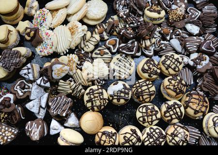Verschiedene Arten frisch zubereiteter Kekse auf einem dunklen Backblech aus Metall. Handdekorierte Kekse. Leckere Backwaren. Stockfoto