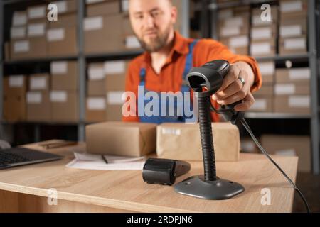 Männlicher Mitarbeiter, der die Barcode-Verpackung von Paketen scannt E-Commerce-Postkartons im Versandzentrum für Direktlieferungen. Stockfoto