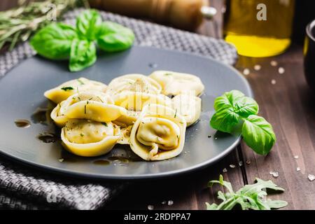 Ravioli mit Basilikum und gemahlenem Pfeffer. Winterrezepte für die kalte Jahreszeit mit italienischer Küche, Blick auf die Vorderseite mit Holzhintergrund Stockfoto
