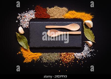 Set mit verschiedenen Gewürzen auf schwarzem Steintisch. Draufsicht mit Kopierbereich. Stockfoto