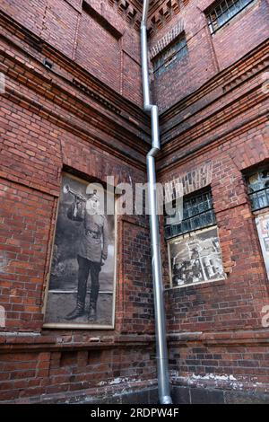 Fassade des Karosta-Gefängnismuseums am ehemaligen russischen Kaiserstützpunkt und sowjetischen Marinestützpunkt an der Ostsee. Reklametafel eines Soldaten Stockfoto