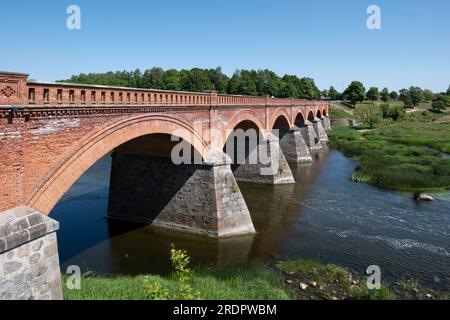 Die alte Backsteinbrücke auf der anderen Seite der Venta ist die längste Brücke dieser Art von Straßenbrücke in Europa. Kuldīga, Lettland Stockfoto