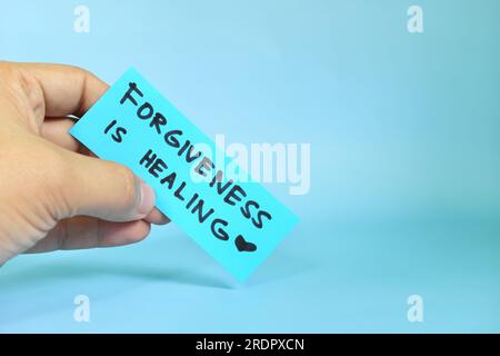 Vergebung ist heilendes Konzept. Eine Hand hält eine blaue Erinnerungsnachricht in der Hand. Stockfoto