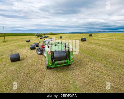 John Anglin ballen runde Silageballen mit Blick auf die Sieben Köpfe in West Cork. Stockfoto