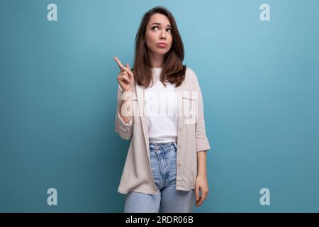 Überraschte 30-jährige Frau in elegantem Look, die auf blauem Hintergrund denkt Stockfoto