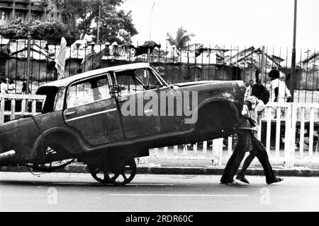 Altes, 1900er Jahre altes Schwarz-Weiß-Bild eines indischen Mannes, der ein gestricktes Fiat-Auto auf einem Handwagen zieht Bombay Mumbai Maharashtra Indien Stockfoto