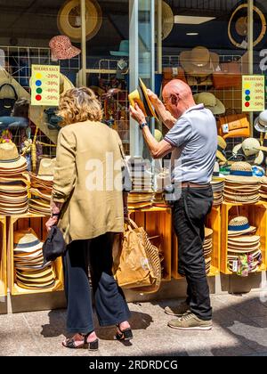 Mann probiert Strohhüte vor dem Hutladen im Stadtzentrum - Loches, Indre-et-Loire (37), Frankreich. Stockfoto