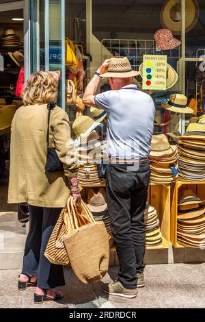 Mann probiert Strohhüte vor dem Hutladen im Stadtzentrum - Loches, Indre-et-Loire (37), Frankreich. Stockfoto