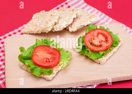 Reiskuchen-Sandwiches mit Tomaten und Salat auf Holzbrett. Einfaches Frühstück. Diät-Essen. Schnelle und gesunde Sandwiches. Knäckebrot mit leckerer Füllung. Gesunder Ernährungs-Snack Stockfoto
