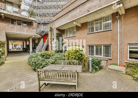 Ein Außenbereich mit einer Holzbank und Feuertreppen im Gebäude ist bis in die zweite Etage versteinert Stockfoto