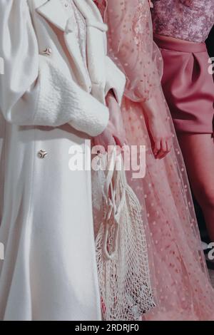 Verkürzte weibliche Figuren in weißem Mantel und pinkfarbenem Kleid auf der Backstage Fashion Week. Trendiges Outfit, kreatives Bekleidungskonzept. Stockfoto