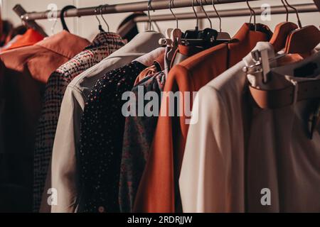 Beigefarbene Designermode-Outfits hängen bei der Backstage Fashion Show hintereinander Stockfoto