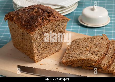 Frischer skandinavischer Laib und Scheiben Sauerteig-Dinkelbrot mit einer Auswahl an Samen aus nächster Nähe auf einem Schneidebrett Stockfoto