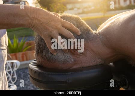 Männlicher Patient, der eine therapeutische Massage von einer weiblichen Masseurin erhält. Stockfoto