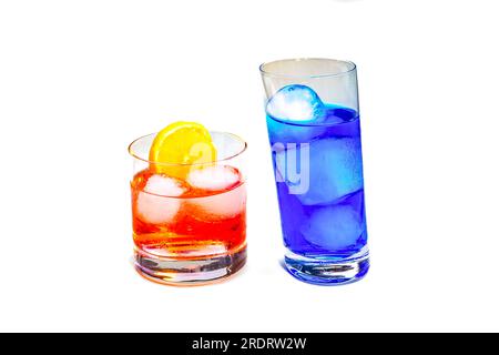 Rote und blaue Cocktails mit Eiswürfeln und einem Stück Zitrone, isoliert im Studio vor weißem Hintergrund Stockfoto