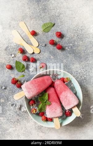 Eis. Sommerdessert. Hausgemachtes Himbeereis mit Joghurt und Himbeeren auf grauem Steinhintergrund. Blick von oben. Stockfoto