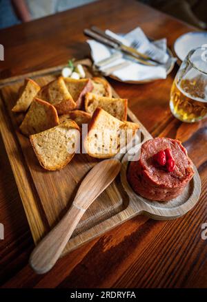 Holztisch mit Tartar Steak und Toast auf Tisch und Bier. Stockfoto