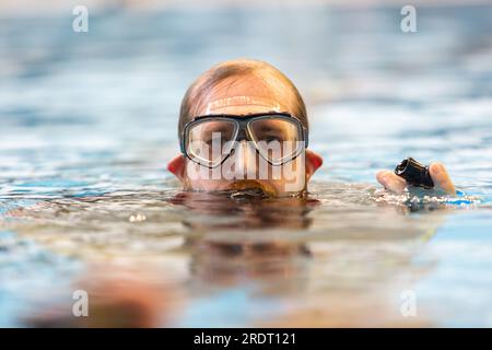 Subaqua-Taucher mit Schutzbrille an der Wasseroberfläche in einem Hallenbad, Großbritannien Stockfoto