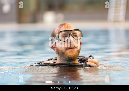 Subaqua-Taucher mit Schutzbrille an der Wasseroberfläche in einem Hallenbad, Großbritannien Stockfoto