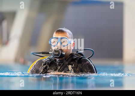 Subaqua-Taucher mit Schutzbrille an der Wasseroberfläche in einem Hallenbad, Großbritannien Stockfoto