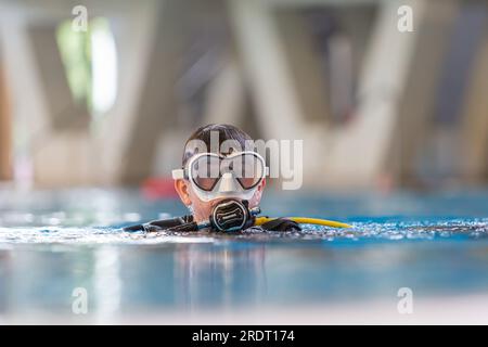 Subaqua-Taucher mit Schutzbrille an der Wasseroberfläche in einem Hallenbad, Großbritannien Stockfoto