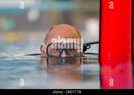 Subaqua-Taucher mit Schutzbrille an der Wasseroberfläche in einem Hallenbad, Großbritannien Stockfoto