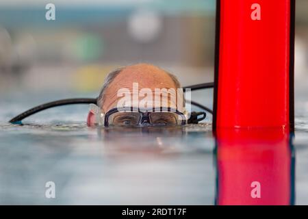 Subaqua-Taucher mit Schutzbrille an der Wasseroberfläche in einem Hallenbad, Großbritannien Stockfoto