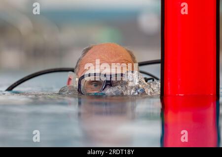 Subaqua-Taucher mit Schutzbrille an der Wasseroberfläche in einem Hallenbad, Großbritannien Stockfoto