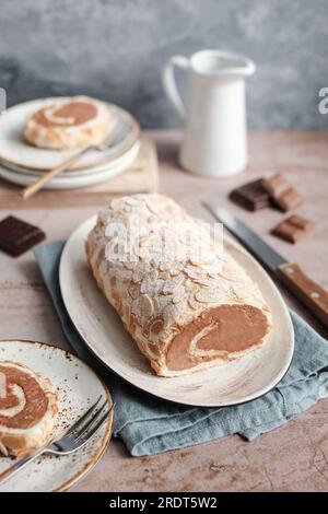 Schokoladen-Baiser-Roulade mit Mandeln. Brauner Hintergrund, blaue Serviette und blauer Hintergrund. Stockfoto