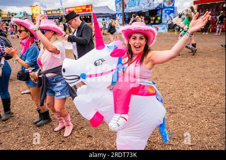 Henham Park, Suffolk, Großbritannien. 23. Juli 2023. Eine Gruppe von Freunden kleidet sich als Cowboys und bringt ein aufblasbares Einhorn mit, um Sophie Ellis-Bextor beim Spielen einer geheimen Akustik auf der kleinen Barclycard-Bühne im „Village“, dem Latitude Festival 2023, Henham Park, zuzusehen. Kredit: Guy Bell/Alamy Live News Stockfoto