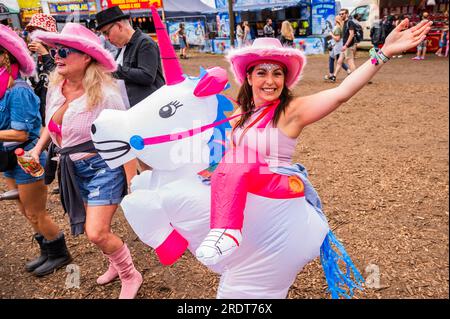 Henham Park, Suffolk, Großbritannien. 23. Juli 2023. Eine Gruppe von Freunden kleidet sich als Cowboys und bringt ein aufblasbares Einhorn mit, um Sophie Ellis-Bextor beim Spielen einer geheimen Akustik auf der kleinen Barclycard-Bühne im „Village“, dem Latitude Festival 2023, Henham Park, zuzusehen. Kredit: Guy Bell/Alamy Live News Stockfoto