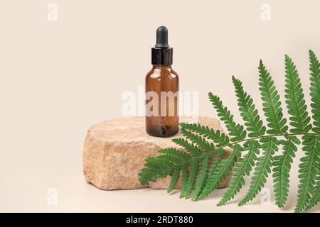 Dunkelbraune Glasflasche, die auf Stein steht. Natürliche Hautpflege SPA Beauty Produktdesign. Mineralölkosmetika. Beiger Hintergrund. Modell. Ölig Stockfoto