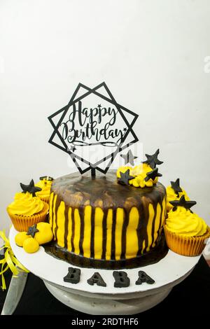 Geburtstagskuchen mit Buttercreme-Glasur und schwarz-gelber Dekoration Stockfoto