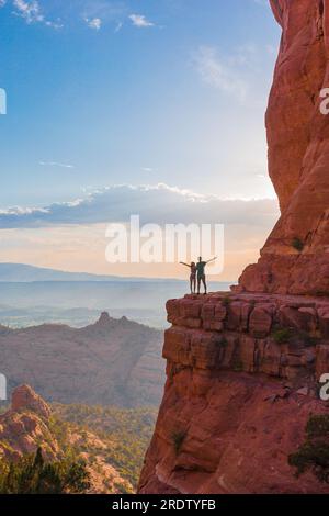 Silhouette von Vater und Tochter auf dem Weg am Cathedral Rock bei Sonnenuntergang in Sedona. Der farbenfrohe Sonnenuntergang über Sedonas Cathedral Rock Wahrzeichen. Stockfoto