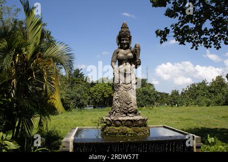 Atemberaubend gefertigte Skulptur einer lächelnden weiblichen Göttin auf einem subtilen Wasserbrunnen im Affenwald in Ubud, Bali, Indonesien Stockfoto