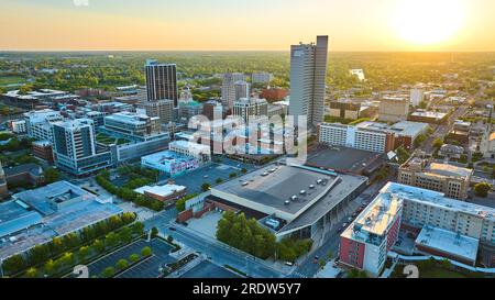 Der Sonnenaufgang in Orange über der Innenstadt mit den Wolkenkratzern und der umliegenden grünen Dachlandschaft der Stadt Stockfoto